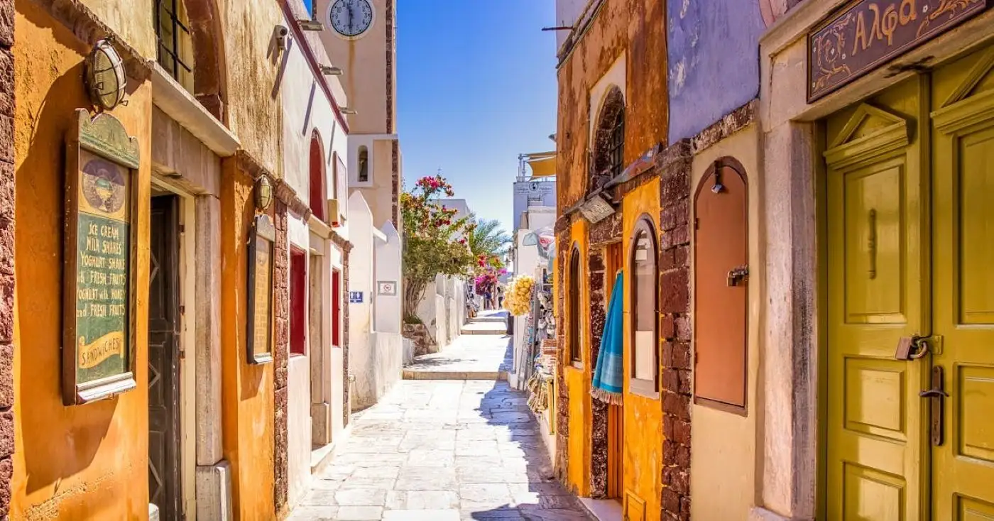Colourful narrow lane in Fira Santorini with traditional stone buildings and bougainvillea